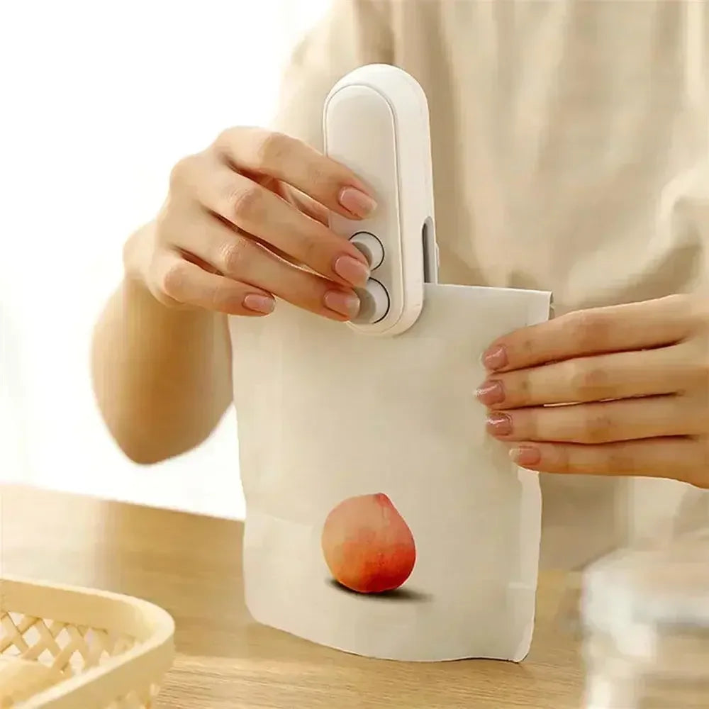 White handheld bag sealer sealing a white pouch with peach image on wooden table